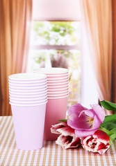 Blue and green plastic glasses with tulips on bright background