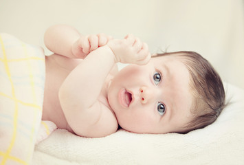 little girl lying on a white cover with blue flower color © Alezhano