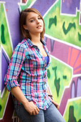 Style teen girl standing near graffiti wall.