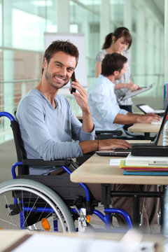 Smiling man in a wheelchair working in an office
