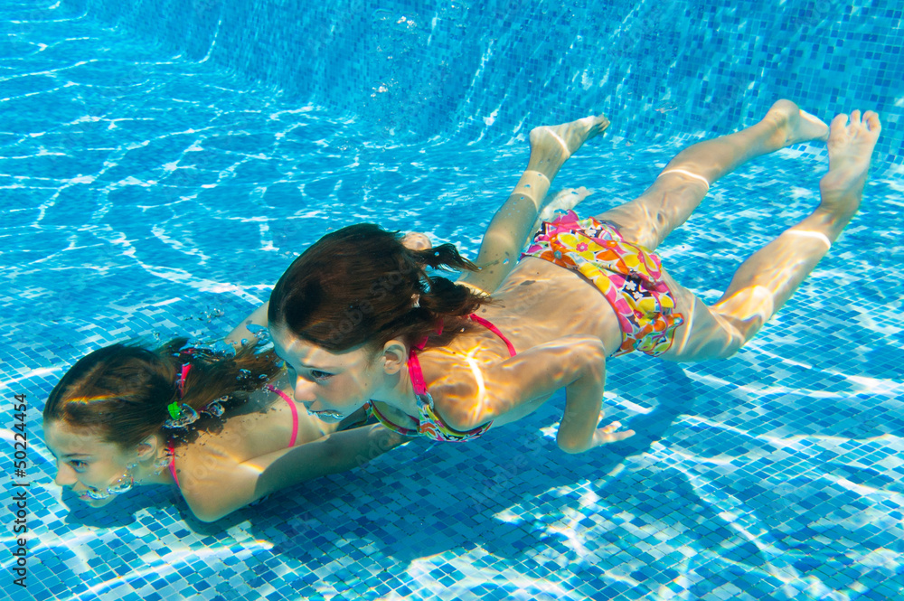 Wall mural underwater kids in swimming pool, girls swim and having fun