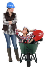 craftswoman accusing her colleague for sitting in wheelbarrow