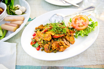 Dried pork with spicy curry on white plate in restaurant