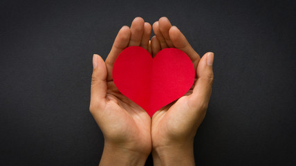 Hands holding a red paper heart