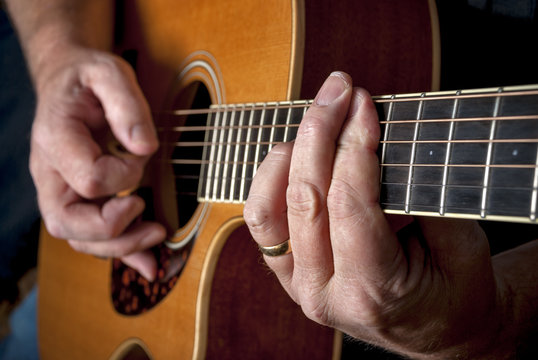 A bar cord is played on a wooden acoustic guitar