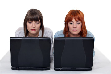 Two young women side by side with laptops