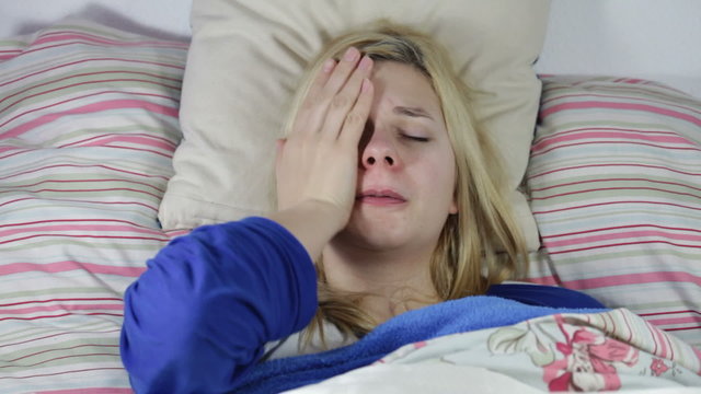 Closeup of tired sick woman coughing in bed