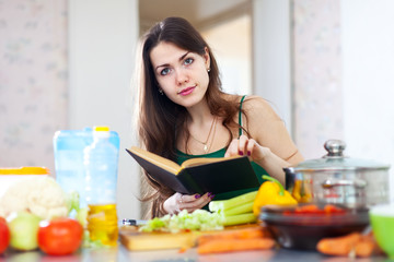 Obraz na płótnie Canvas young woman reads cookbook for recipe