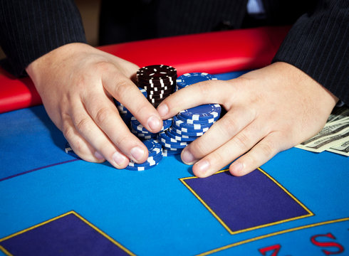 men's hand with chips, cards and dollars banknotes on table