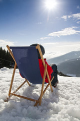 Women at mountains in winter lies on sun-lounger