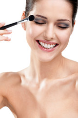 Fototapeta premium Woman putting on make-up with brush, isolated on white
