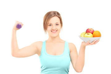 Beautiful young female posing with a dumbbell and fruits in a bo