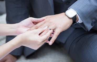 bride's hand putting a wedding ring on the groom's finger
