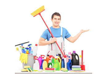 Man in a uniform holding a broom and posing with cleaning suppli