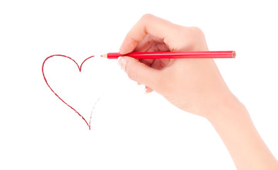 Woman's hand holding a red pencil and drawing a heart