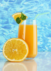 Glass of orange juice with mint and orange on sea background