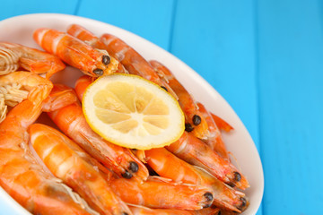 Shrimps with lemon on plate on wooden table close-up