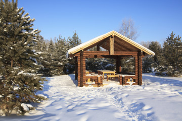 Wooden gazebo in the winter forest.