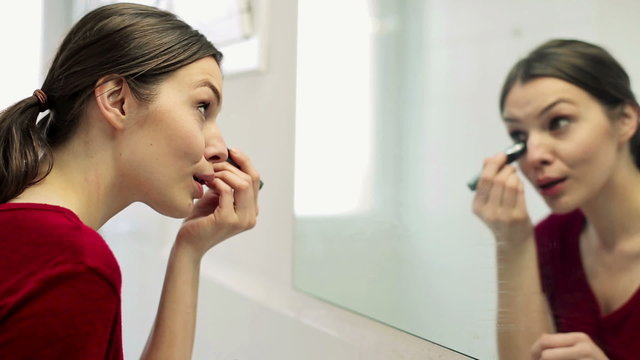 Young beautiful woman applying concealer on her face