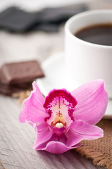 cup of coffee, chocolate and orchid on wooden background