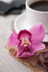 Obraz na płótnie Canvas cup of coffee, chocolate and orchid on wooden background