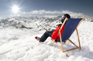 Women at mountains in winter lies on sun-lounger