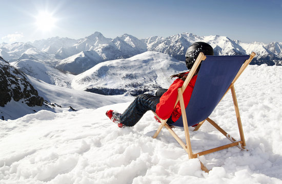 Women at mountains in winter lies on sun-lounger