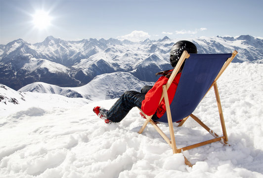Women at mountains in winter lies on sun-lounger