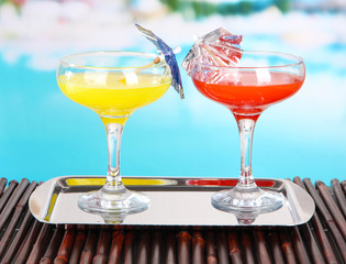 Glasses of cocktails on table near pool