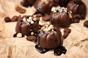Chocolate candies and coffee beans, on beige paper background