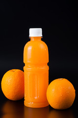 orange juice in a bottle and orange  on black background