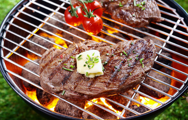Steak grilling over a glowing fire