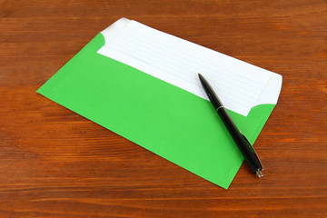 Envelope with pen on wooden background