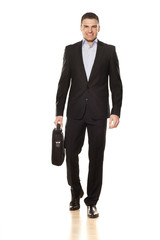 attractive smiling young businessman walking with a laptop bag