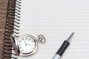 Pocket watch ballpoint pen on notebook for notes close-up.