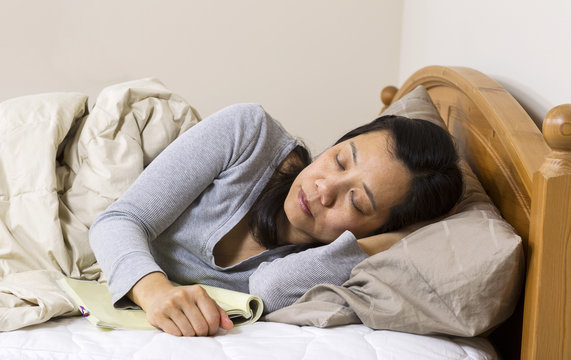 Mature woman falling asleep with book next to her