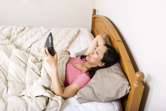 Mature woman looking at alarm clock while trying to sleep