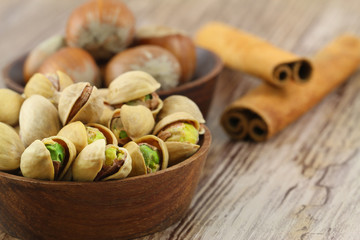 Pistachios, hazelnuts and cinnamon sticks on wooden background