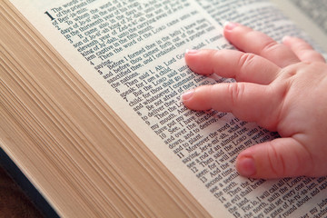 Obraz premium Baby Hand on Open Bible