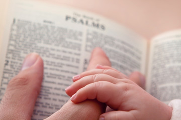 Obraz premium Baby Holding Dad’s Finger on Bible