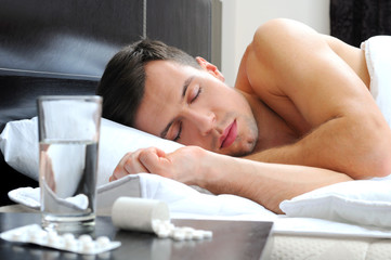 Obraz na płótnie Canvas Man sleeping - pills on bed table