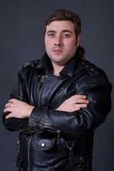 Fototapeta na wymiar young man in a leather jacket on a gray background