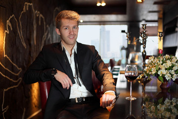 Smile young man in a black suit at the bar