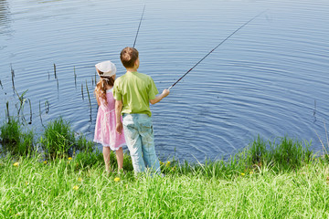 Boy in green t-shirt and his sister in pink dress fish in pond