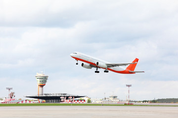 Large red and white passenger airplane takes off at airport.