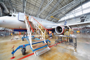 Repairing plane in hangar - obrazy, fototapety, plakaty