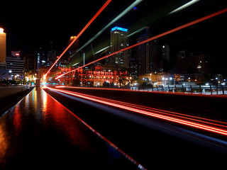 Motion blur effect caused by red taillights of fast driving bus creating light trails at night Brisbane city center in Australia 