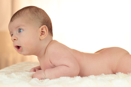 Cute naked baby boy lies on his stomach