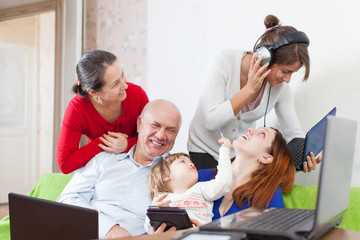 Happy multigeneration family uses electronic devices