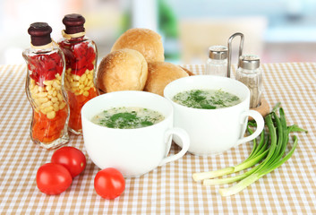 Fragrant soup in cups on table in kitchen